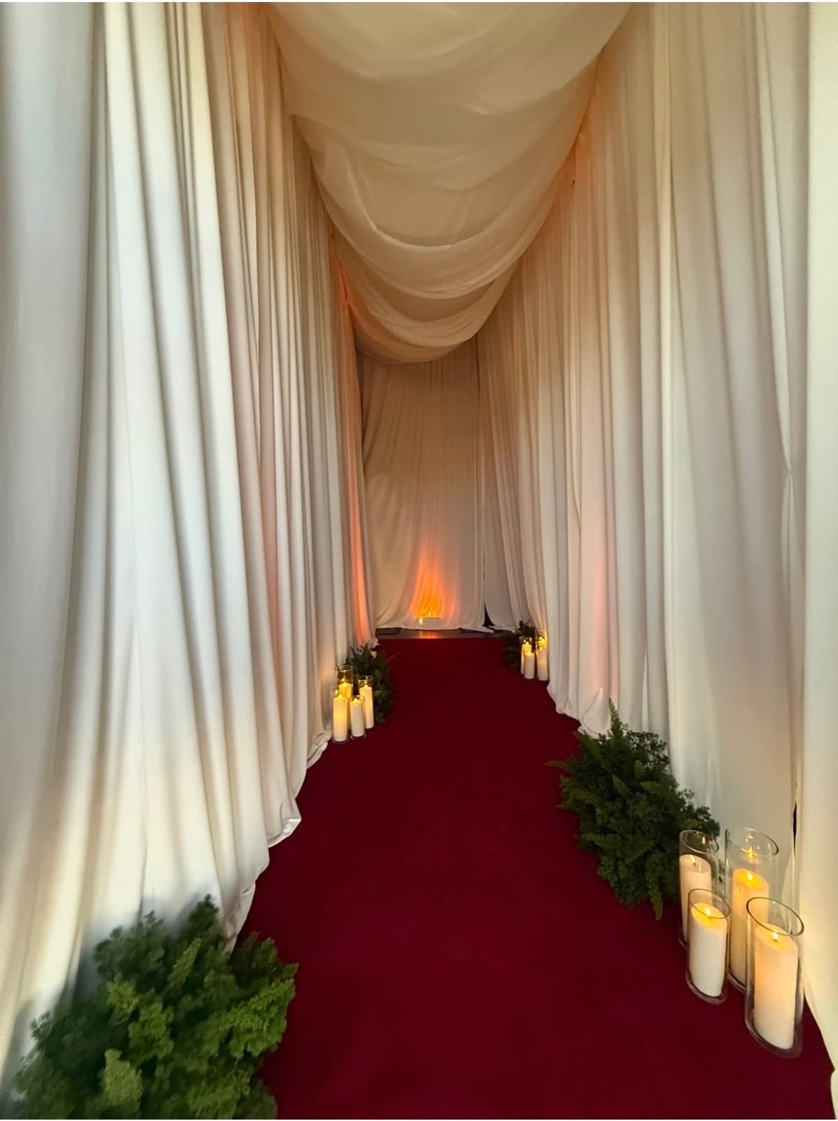 White wedding drapery aisle with red carpet, candles and greenery — Las Vegas pipe and drape